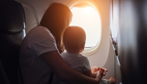 Joyful,Mother,Shows,View,From,Plane,Window,To,Toddler,Girl.