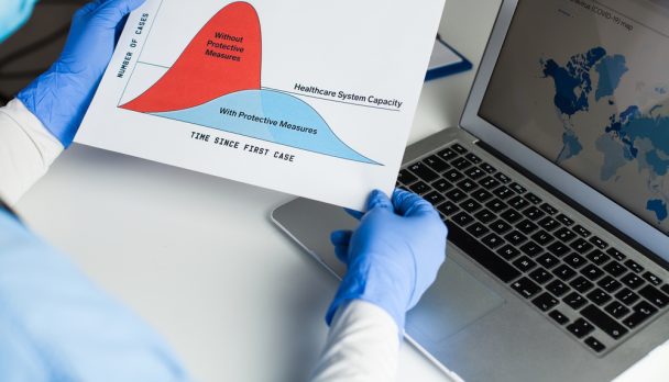 Doctor,Wearing,Protective,Gloves,Holding,Flatten,The,Curve,Chart,,Sitting