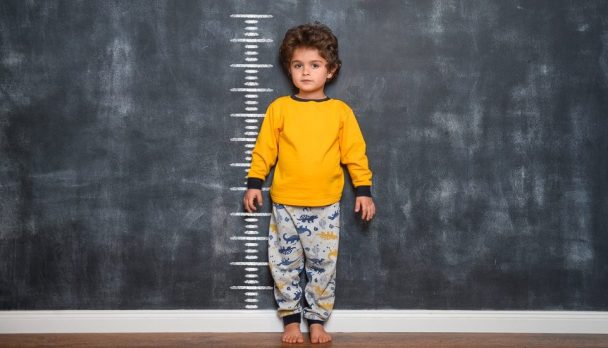 Funny,Smiling,Little,Child,With,Measures,Of,Growth,On,Blackboard